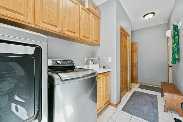 washroom featuring cabinet space, independent washer and dryer, and light tile patterned floors