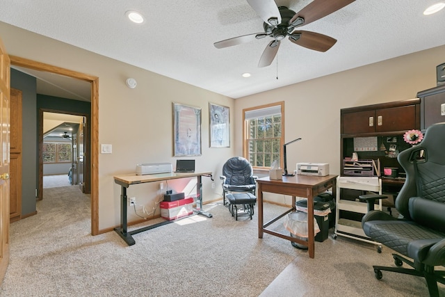 office space featuring ceiling fan, light colored carpet, plenty of natural light, recessed lighting, and a textured ceiling