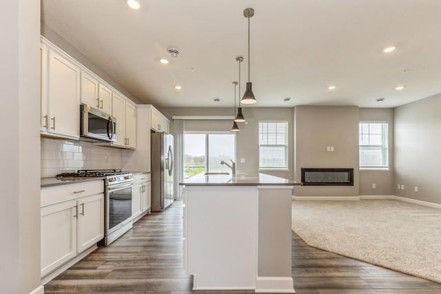 20023 62nd Pl, Corcoran, MN 55340 - kitchen featuring appliances with stainless steel finishes, open floor plan, recessed lighting, an island with sink, and backsplash
