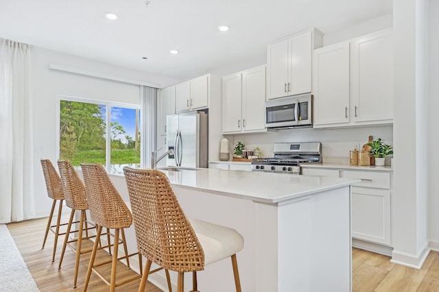 20023 62nd Pl, Corcoran, MN 55340 - kitchen with stainless steel appliances, a center island with sink, recessed lighting, light wood-style floors, and white cabinetry