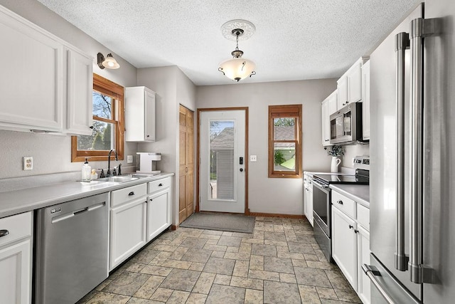 681 4th St NE, Little Falls, MN 56345 - kitchen featuring stainless steel appliances, healthy amount of natural light, white cabinetry, a sink, and a textured ceiling