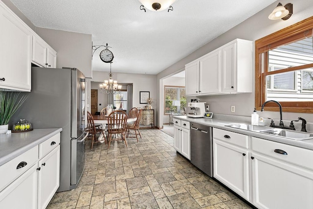 681 4th St NE, Little Falls, MN 56345 - kitchen featuring appliances with stainless steel finishes, a sink, a chandelier, white cabinetry, and light countertops