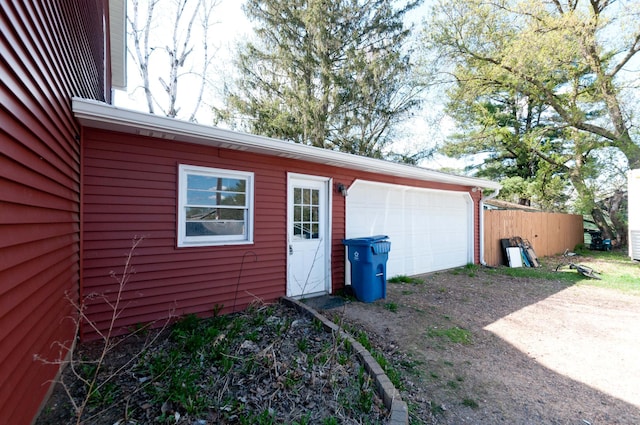 garage featuring dirt driveway and fence