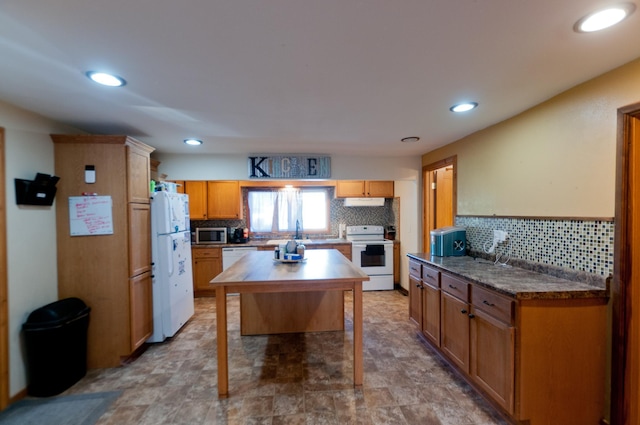 kitchen featuring white appliances, decorative backsplash, recessed lighting, a kitchen island, and a sink