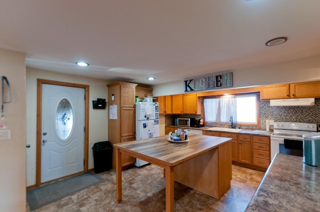 kitchen with white appliances, under cabinet range hood, backsplash, a sink, and recessed lighting