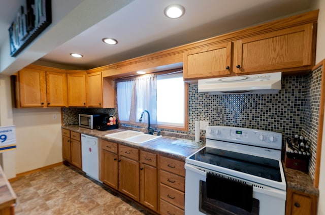 kitchen featuring white appliances, a sink, under cabinet range hood, tasteful backsplash, and dark countertops