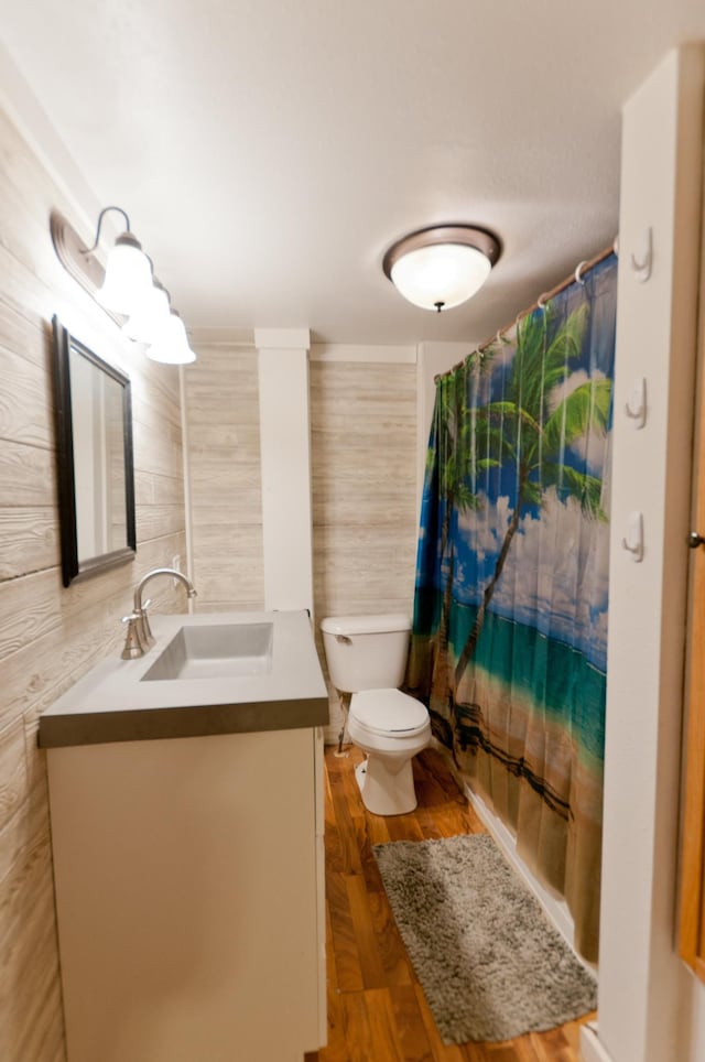 bathroom featuring tile walls, vanity, toilet, curtained shower, and wood finished floors