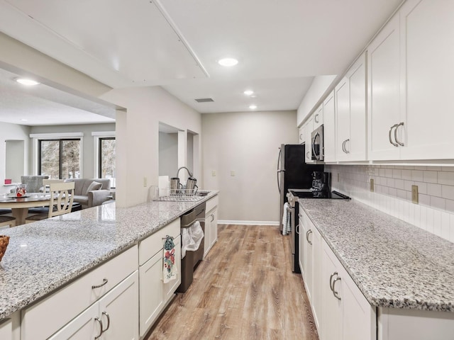 7520 Cahill Rd Unit 222A, Edina, MN 55439 - kitchen with appliances with stainless steel finishes, white cabinetry, light wood-style flooring, light stone countertops, and baseboards