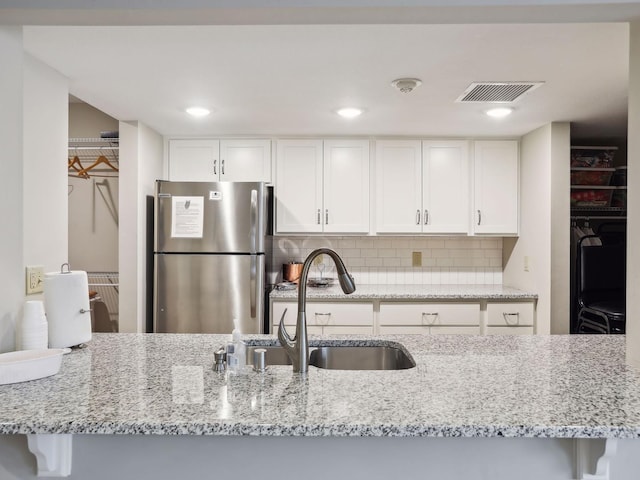 7520 Cahill Rd Unit 222A, Edina, MN 55439 - kitchen featuring freestanding refrigerator, a sink, backsplash, light stone countertops, and white cabinetry