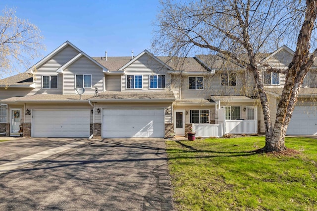 multi unit property with asphalt driveway, an attached garage, and a front lawn