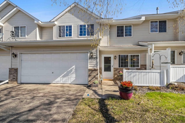townhome / multi-family property featuring an attached garage, asphalt driveway, and fence