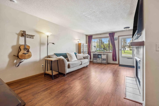 living area featuring a textured ceiling, wood finished floors, and baseboards