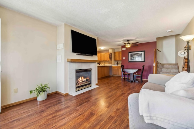 living room featuring dark wood finished floors, stairway, a tile fireplace, a textured ceiling, and baseboards