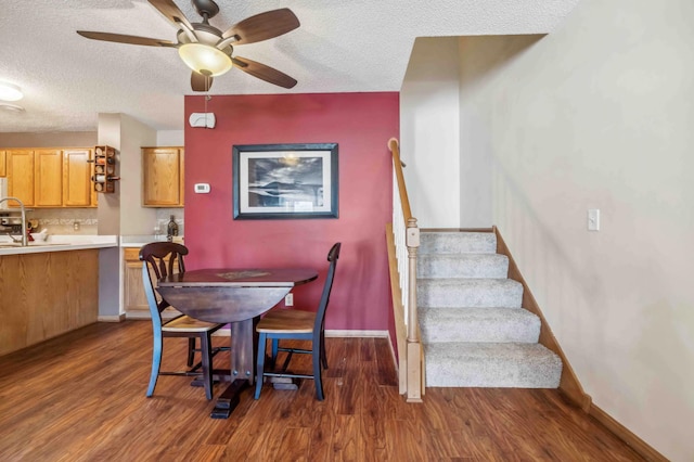 dining space with a textured ceiling, dark wood-style flooring, stairs, a ceiling fan, and baseboards