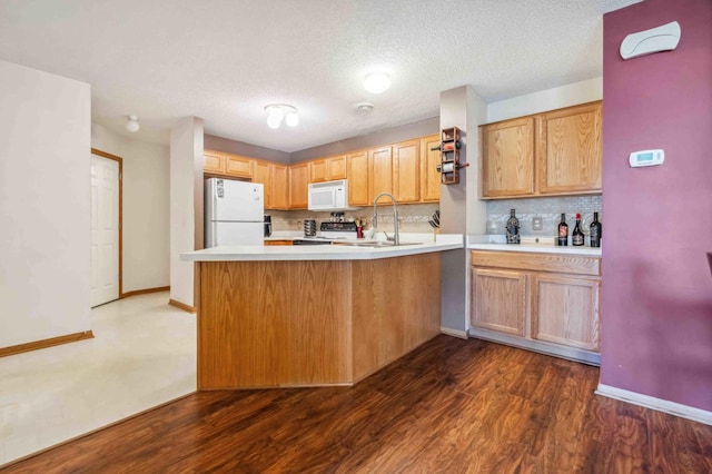 kitchen with white appliances, a peninsula, a sink, decorative backsplash, and a textured ceiling