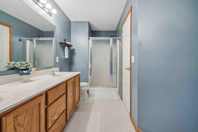 bathroom with a shower stall, a textured ceiling, toilet, double vanity, and tile patterned floors