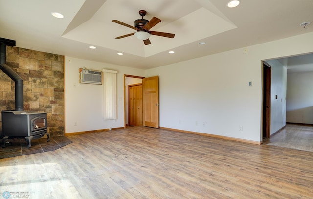 10544 40th St N, Kragnes Twp, MN 56560 - unfurnished living room with a raised ceiling, a wall mounted AC, a ceiling fan, a wood stove, and wood finished floors