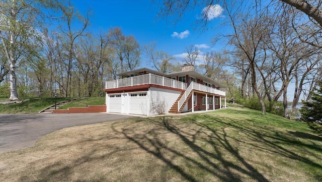 view of front of home with stairway, driveway, a chimney, a front yard, and an attached garage