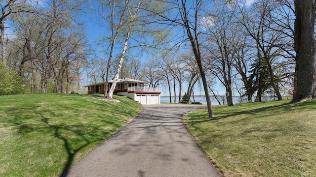 view of community with a water view, a lawn, a garage, and driveway
