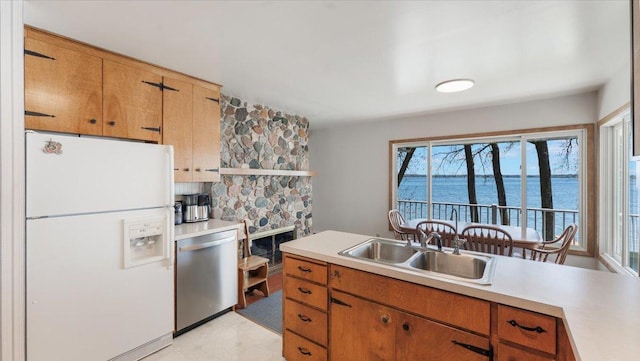 kitchen with white refrigerator with ice dispenser, dishwasher, a sink, light countertops, and a water view