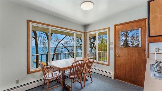 carpeted dining area with baseboard heating and a water view