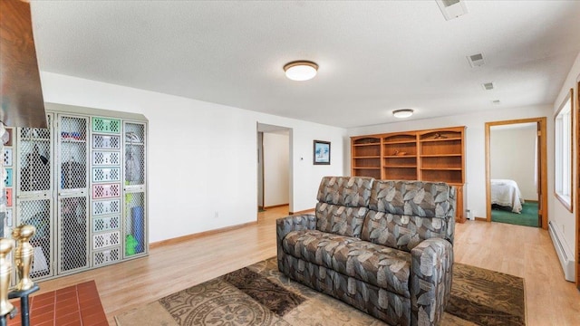 living room with wood finished floors, a baseboard heating unit, and baseboards