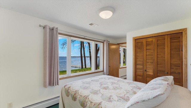 bedroom with a baseboard radiator, a water view, and a closet