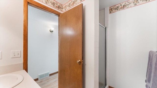 full bath with a shower stall, wood finished floors, and vanity