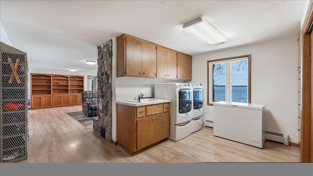laundry room with cabinet space, a baseboard heating unit, separate washer and dryer, light wood-style floors, and a textured ceiling