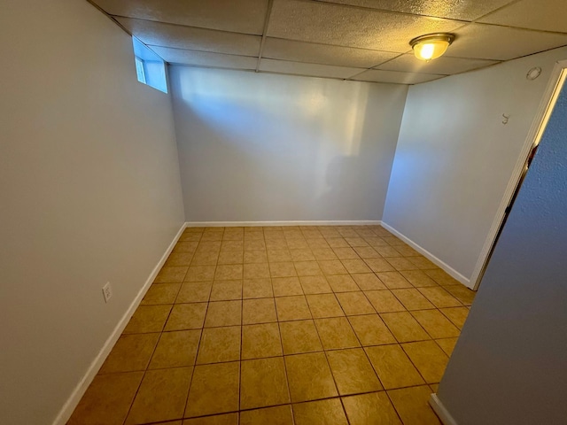 below grade area featuring a paneled ceiling, tile patterned floors, and baseboards
