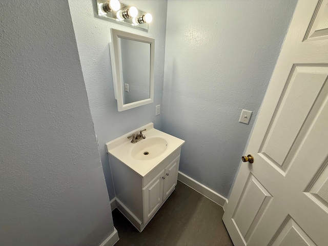 bathroom with baseboards, vanity, and a textured wall