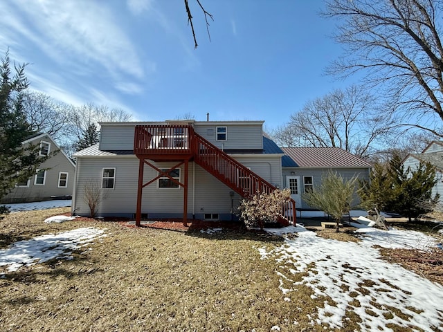 snow covered back of property with stairs, metal roof, and a wooden deck