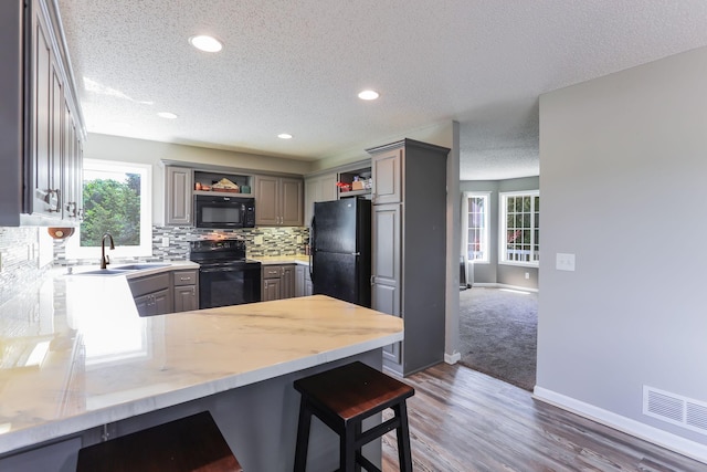 18071 Lincoln Cir NW, Elk River, MN 55330 - kitchen featuring black appliances, open shelves, a peninsula, a textured ceiling, and a sink