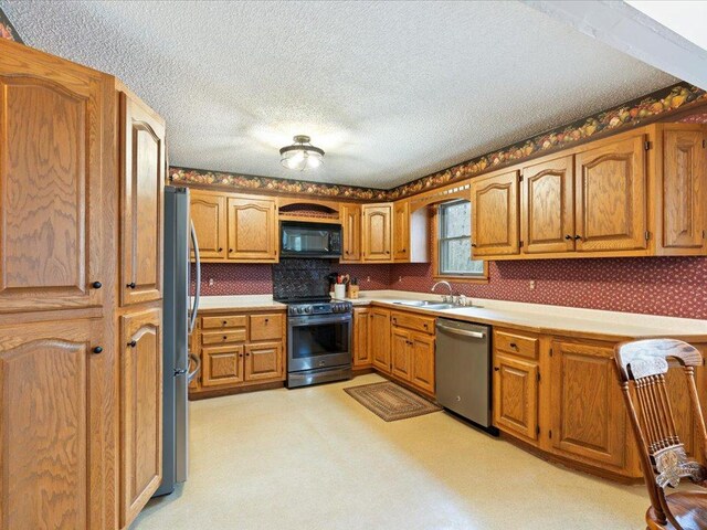19531 Pine Landing Dr, Grand Rapids, MN 55744 - kitchen featuring appliances with stainless steel finishes, a sink, light countertops, brown cabinetry, and a textured ceiling