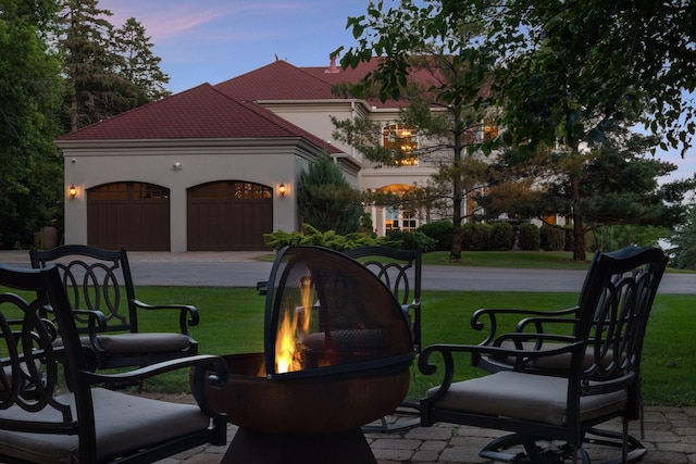 1860 Shoreline Dr, Orono, MN 55391 - patio terrace at dusk with a yard, an outdoor fire pit, a garage, and driveway