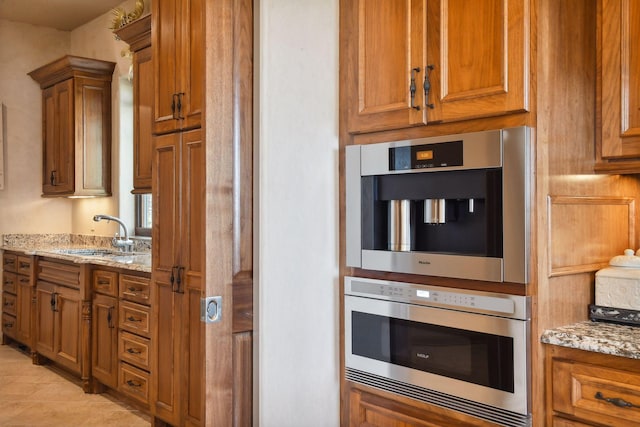 1860 Shoreline Dr, Orono, MN 55391 - kitchen featuring a sink, brown cabinets, light stone counters, and light tile patterned floors