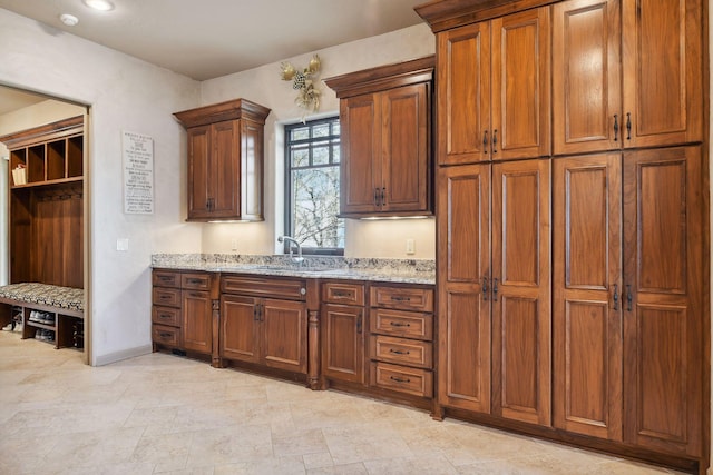 1860 Shoreline Dr, Orono, MN 55391 - kitchen with a sink, light stone counters, brown cabinetry, and baseboards
