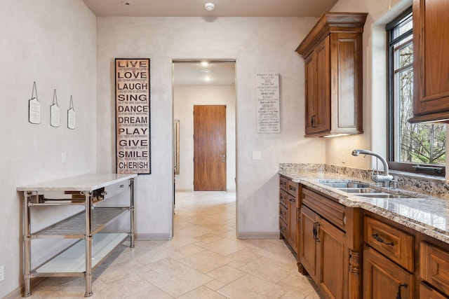 1860 Shoreline Dr, Orono, MN 55391 - kitchen featuring a sink, baseboards, brown cabinetry, and light stone counters