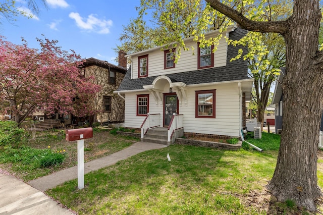 view of front of home with roof with shingles and a front lawn