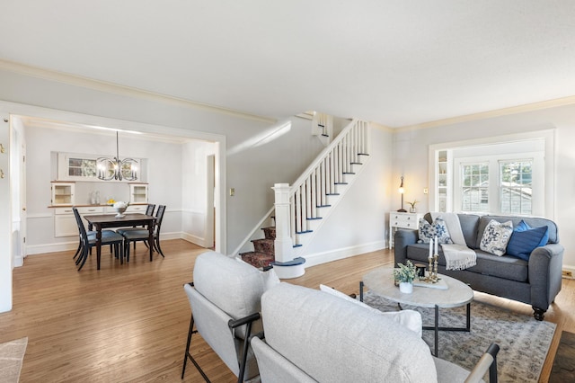 living room featuring stairway, a chandelier, ornamental molding, light wood-style flooring, and baseboards