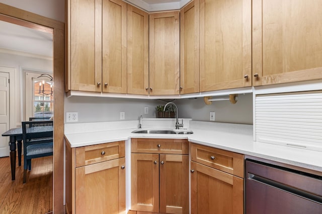 kitchen with a sink, dishwasher, wood finished floors, light countertops, and crown molding