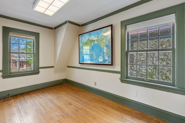 empty room with ornamental molding, light wood-type flooring, a baseboard heating unit, and baseboards