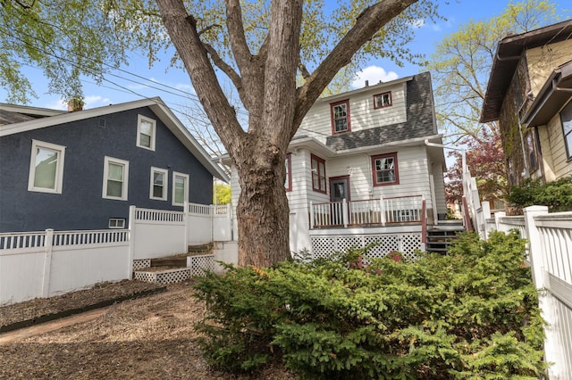 view of front facade featuring fence, a wooden deck, and roof with shingles