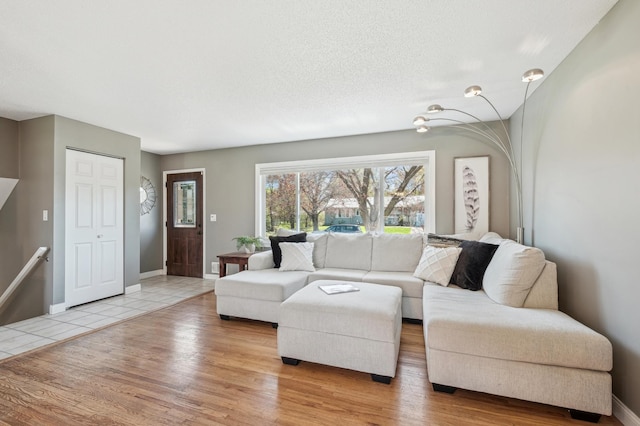living area featuring light wood-style floors, baseboards, and a textured ceiling