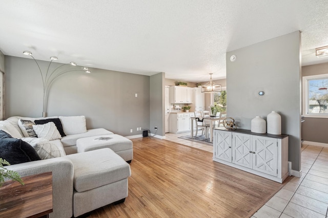 living area featuring a textured ceiling, healthy amount of natural light, baseboards, and light tile patterned floors