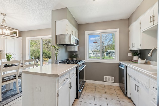 kitchen featuring appliances with stainless steel finishes, a sink, white cabinets, light countertops, and a textured ceiling