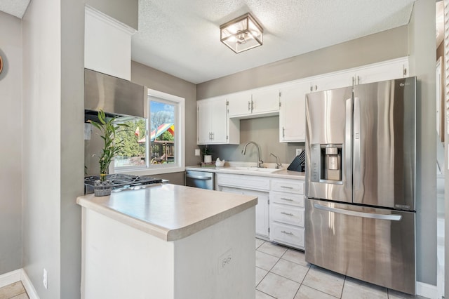 kitchen with stainless steel appliances, a textured ceiling, light countertops, a sink, and exhaust hood