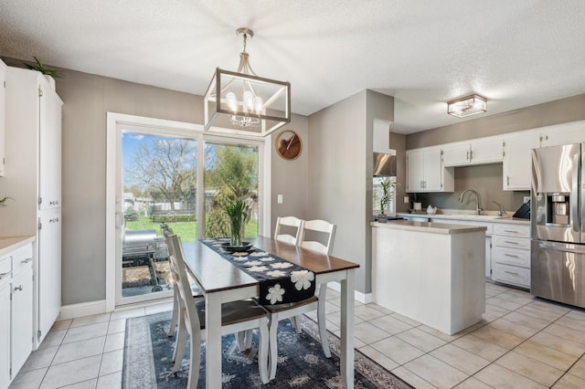 kitchen featuring stainless steel refrigerator with ice dispenser, light countertops, a textured ceiling, light tile patterned floors, and white cabinetry
