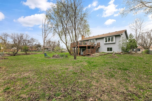 rear view of house featuring a wooden deck, a fire pit, a lawn, and a chimney