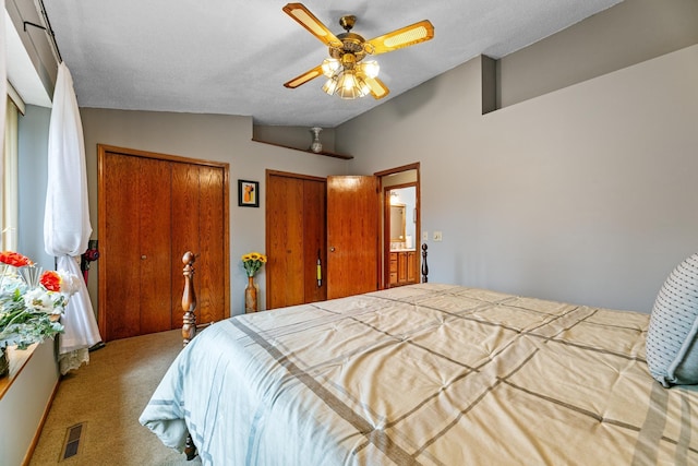 bedroom with carpet floors, lofted ceiling, two closets, and a ceiling fan
